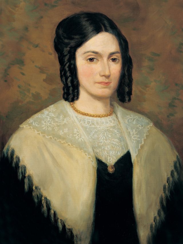 A painted portrait of Emma Smith. She wears a black dress with a white collar portion. She wears a white and yellow shawl over her shoulders. Her hair is black and has several long, tight curls that fall from her temples.