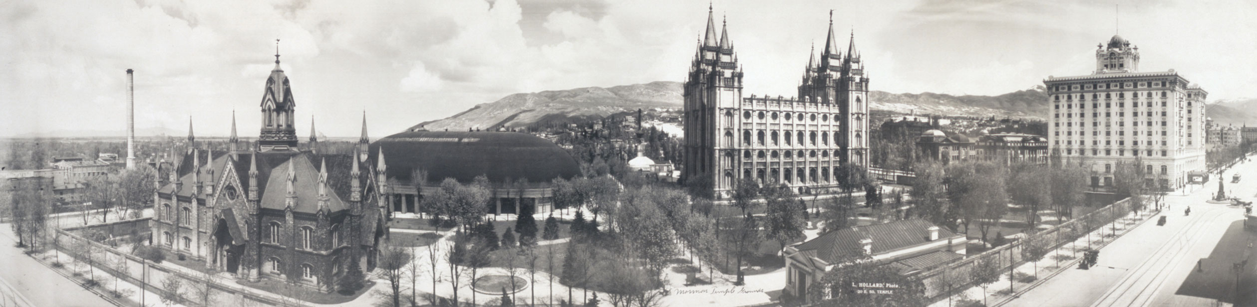 A panoramic, black-and-white image of temple square. Notable landmarks from left to right are the chapel, the tabernacle, the temple, and the church administration building.