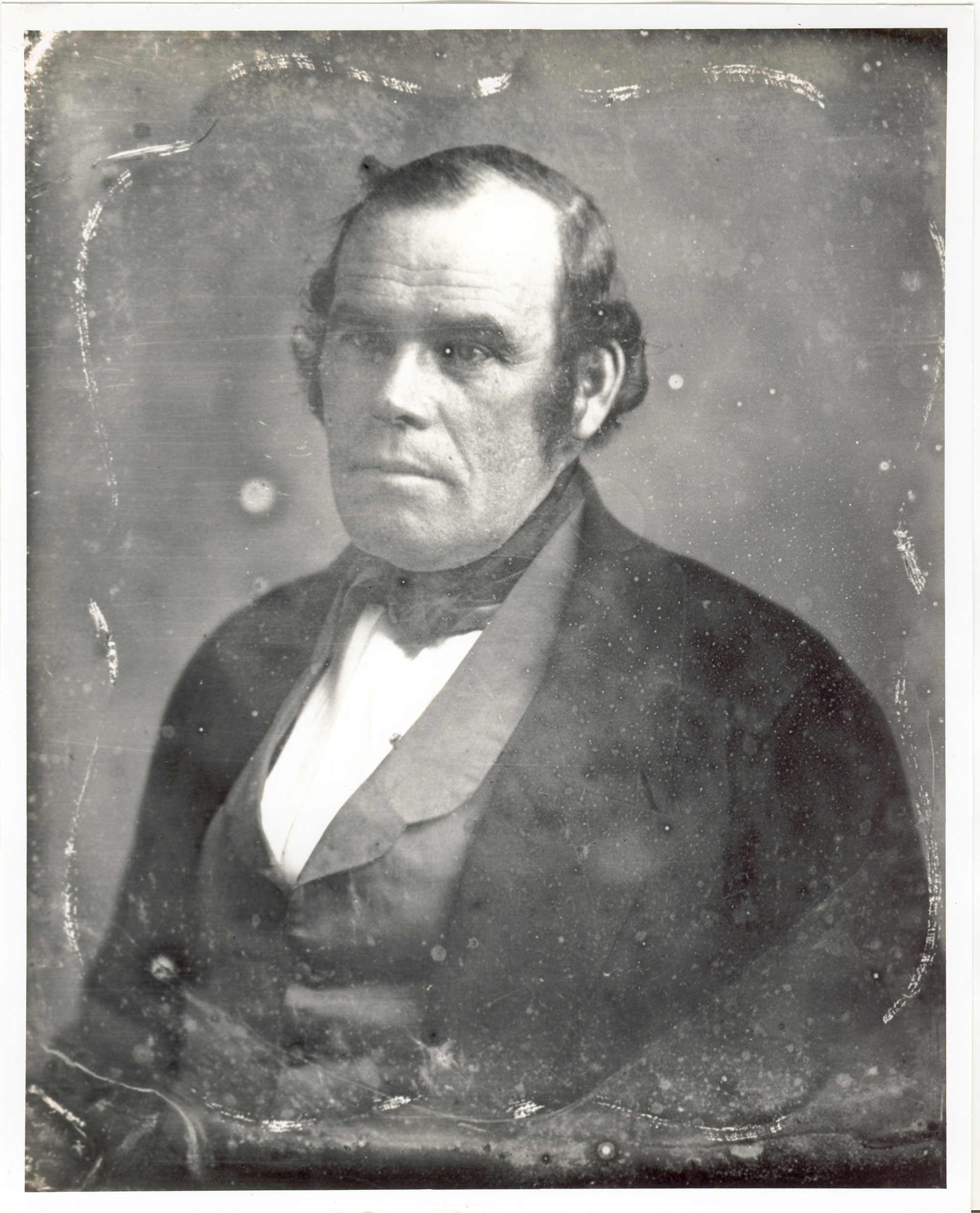 A black-and-white, faded photo of Parley P. Pratt. He wears a white shirt, midtone vest, black coat, and black cravat. 