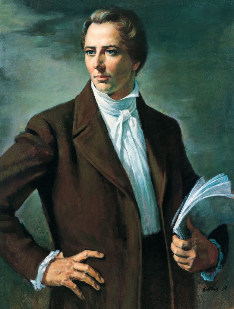 A painting of Joseph Smith. He wears a brown suit coat and white shirt and tie. He has his right hand on his hip and a collection of papers in his left hand.